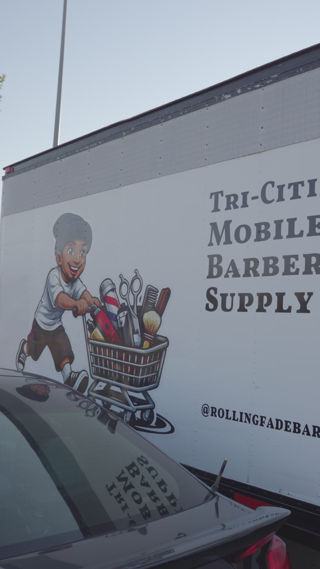 El tráiler rotulado de Tri-Cities Mobile Barber Supply con la mascota